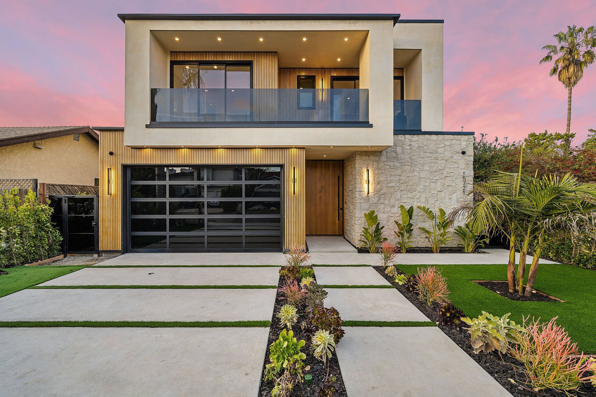 Modern two-story home with glass garage door upper balcony and stone accent wall in El Dorado Hills.