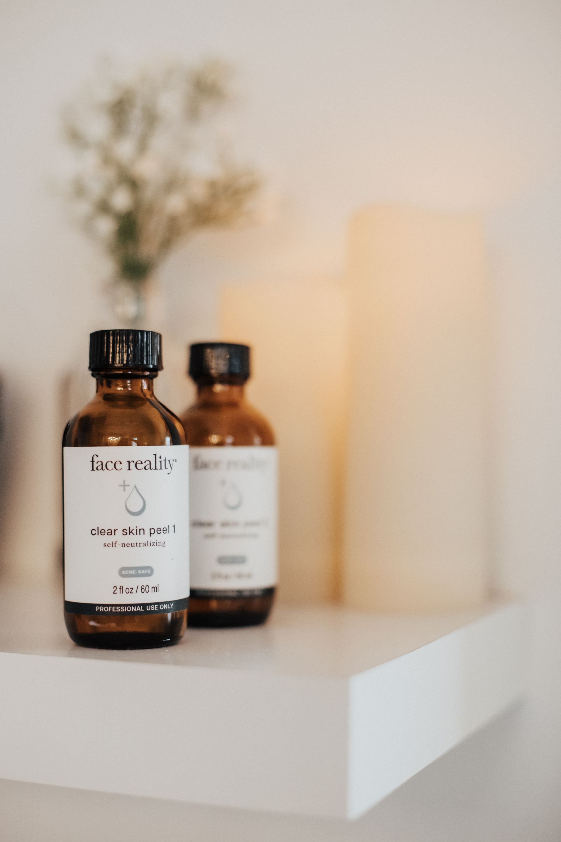 Two brown bottles with black caps and labels on a white shelf.