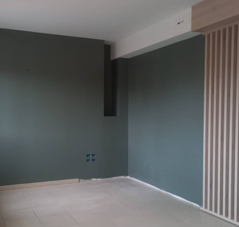 Alto palazzo residenziale in mattoni in costruzione, con impalcature, recinzioni di sicurezza arancioni e auto parcheggiate su una strada cittadina.