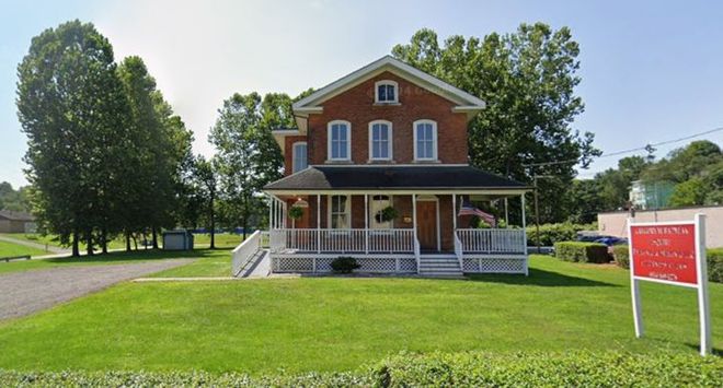 Brick historic house with white porch on a sunny green lawn Brick historic house with white porch on a sunny green lawn