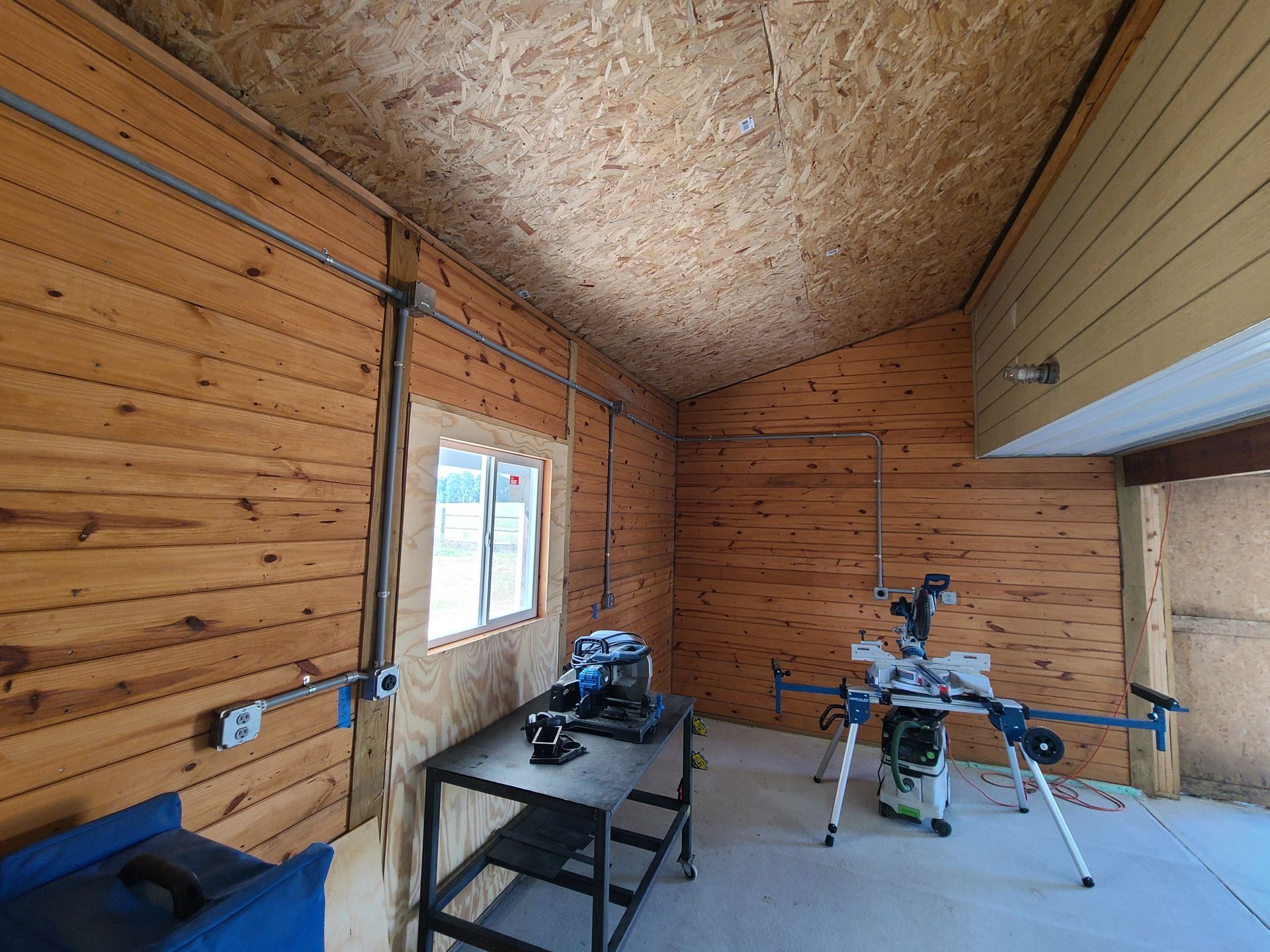 A wooden garage with a table and a saw in it