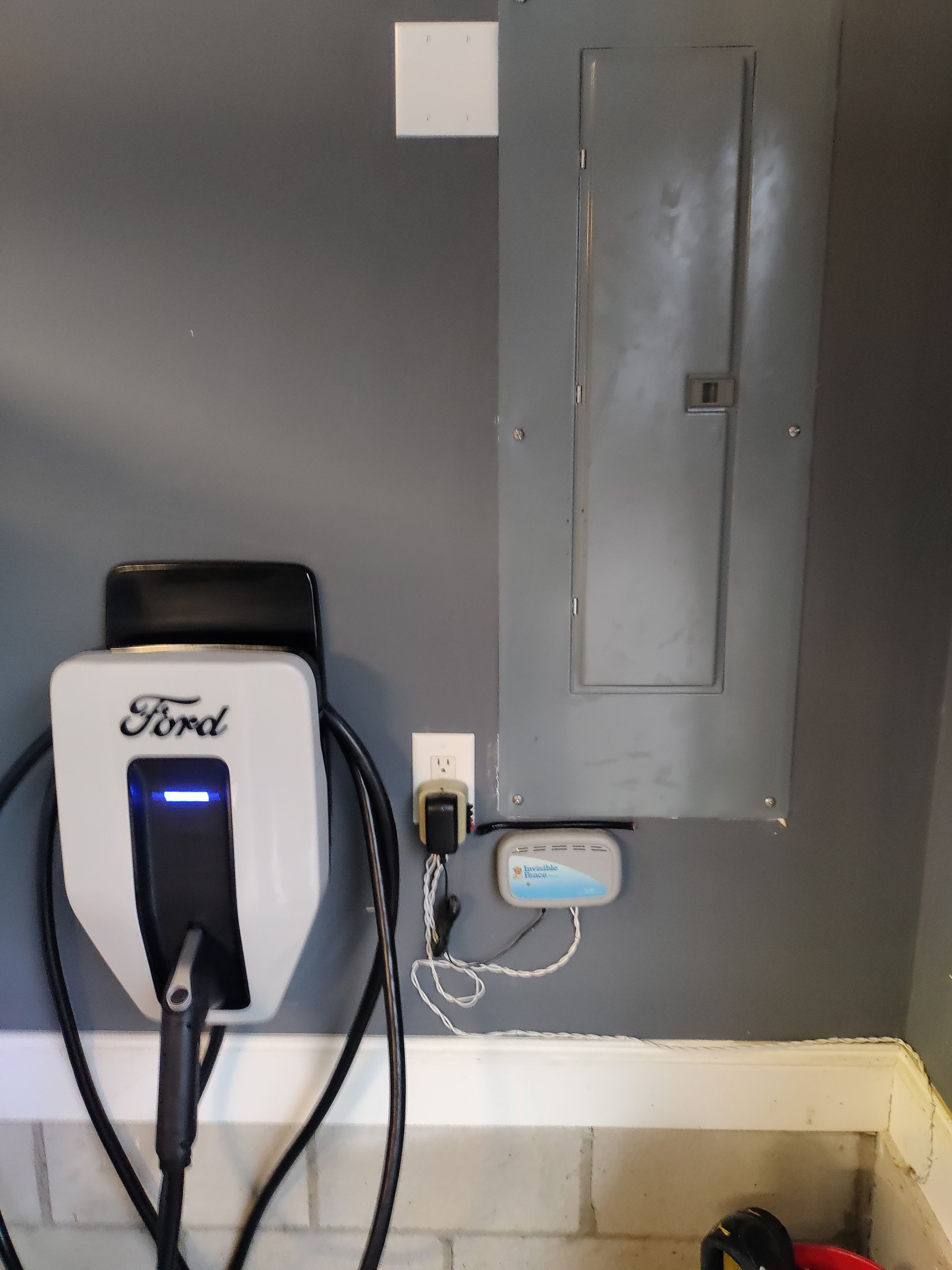 A ford electric car charger is plugged into a wall.