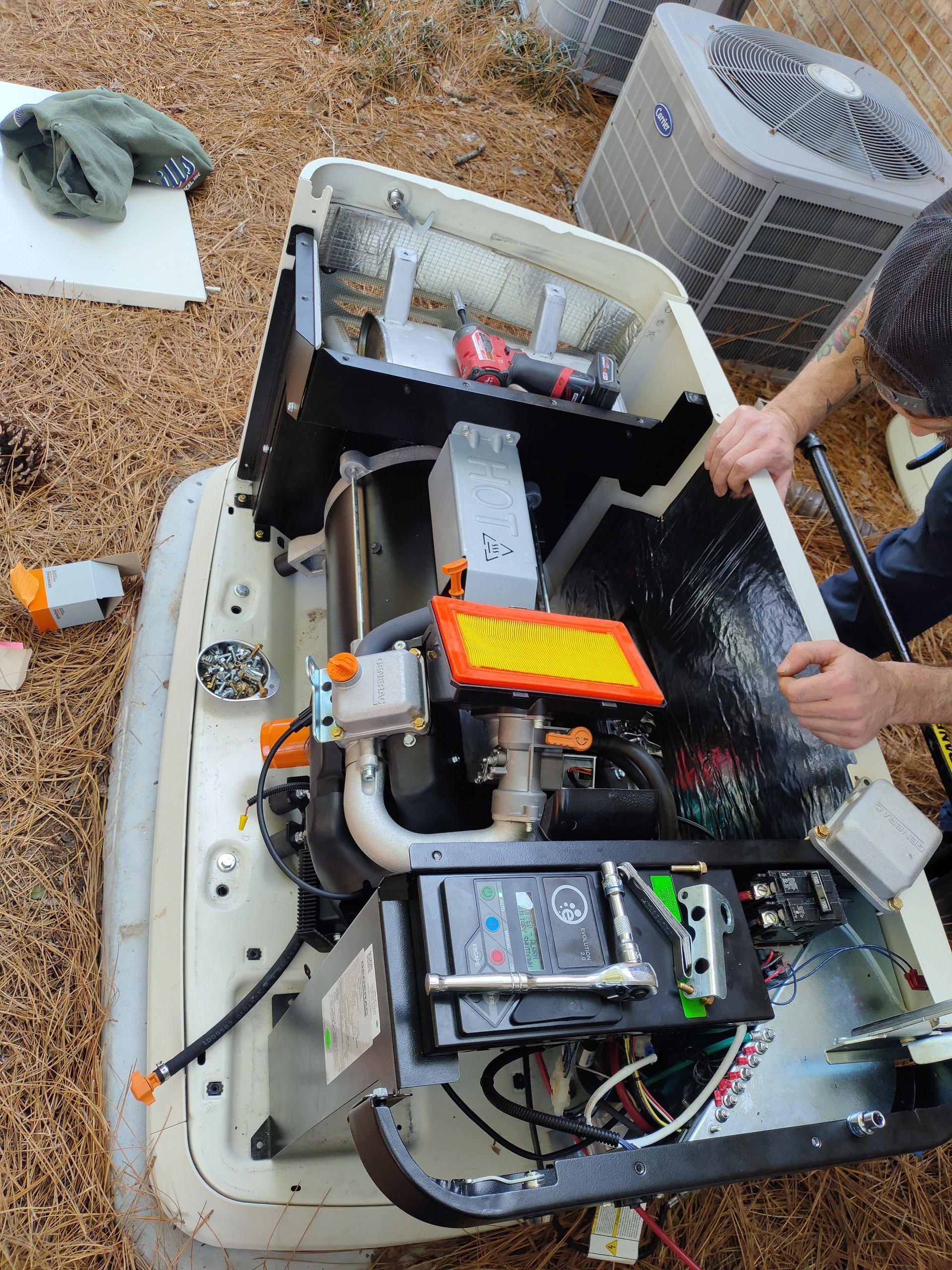 A man is working on a generator outside of a house.