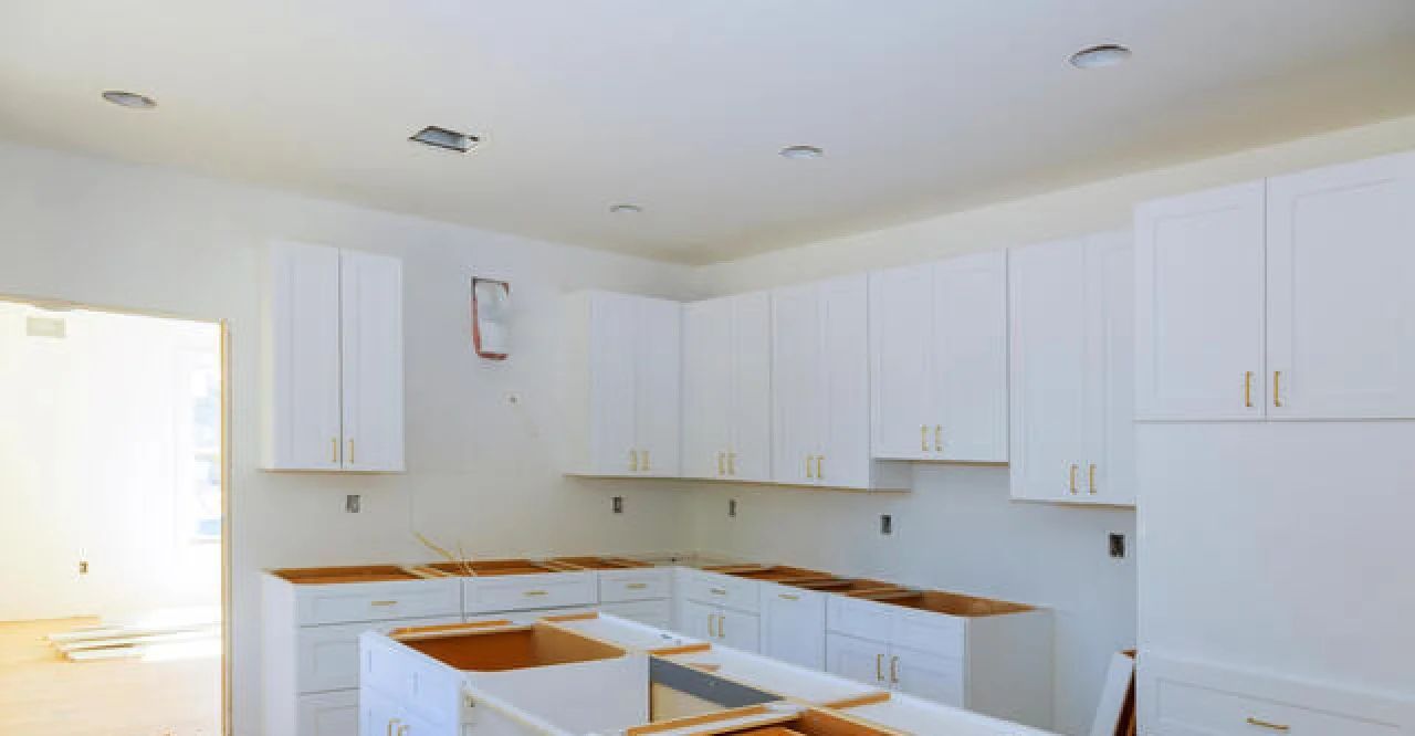 Bright white unfinished kitchen with cabinets, countertops, and ceiling lights in place