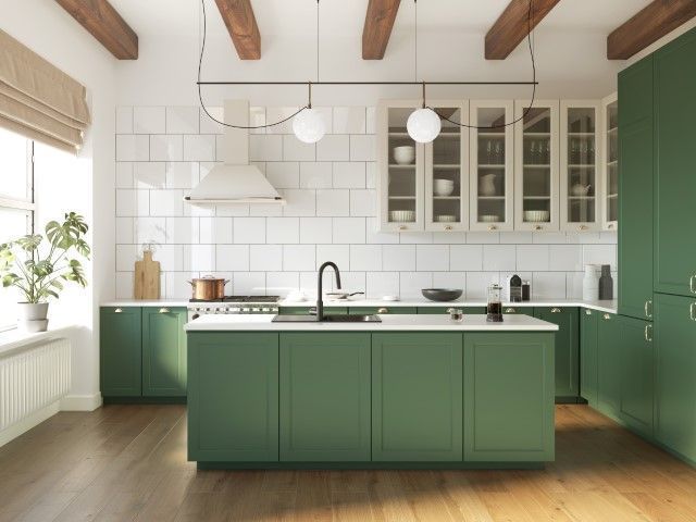 Bright modern kitchen with green cabinets, white tile backsplash, island, and wood ceiling beams