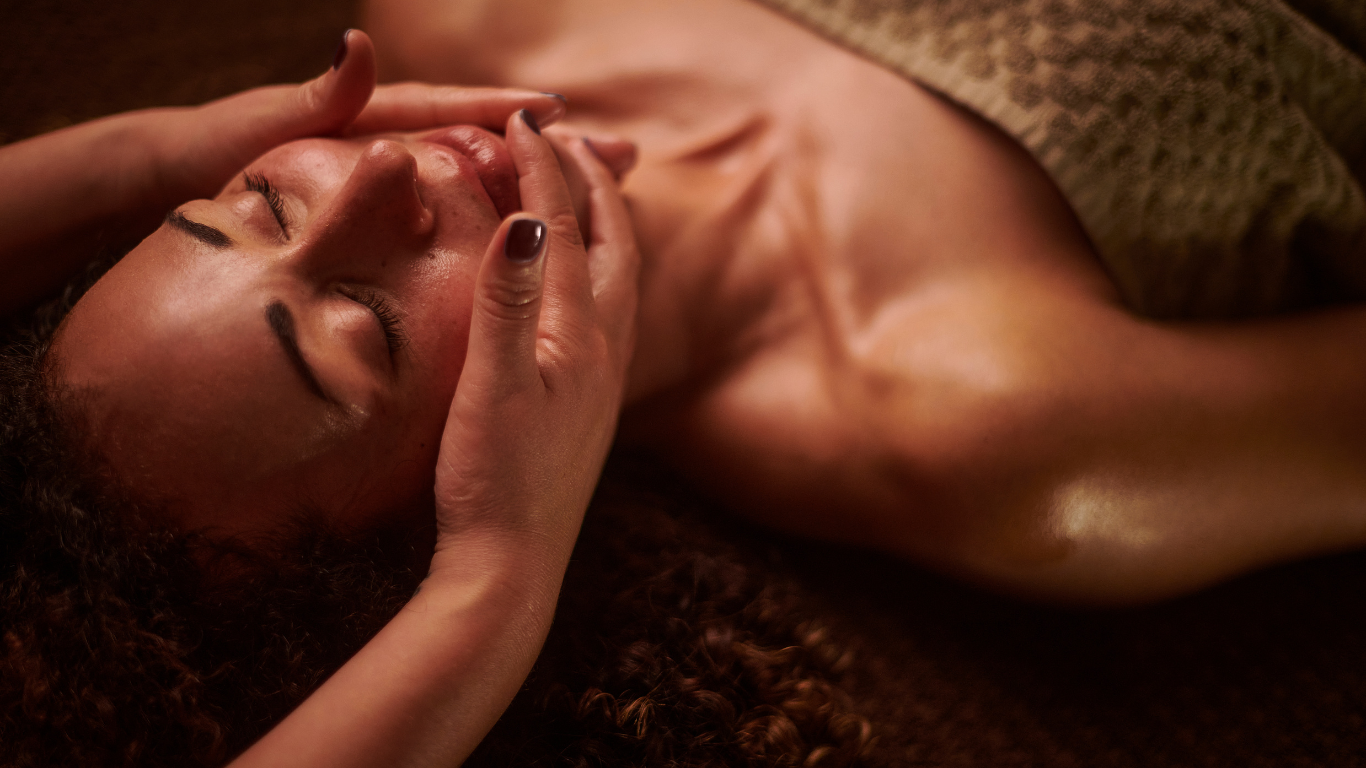 a woman is laying on a bed getting a massage on her face .