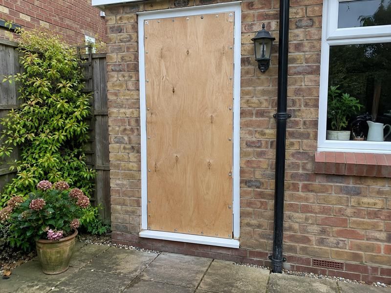 Back door of a house covered by a board, seen from the garden