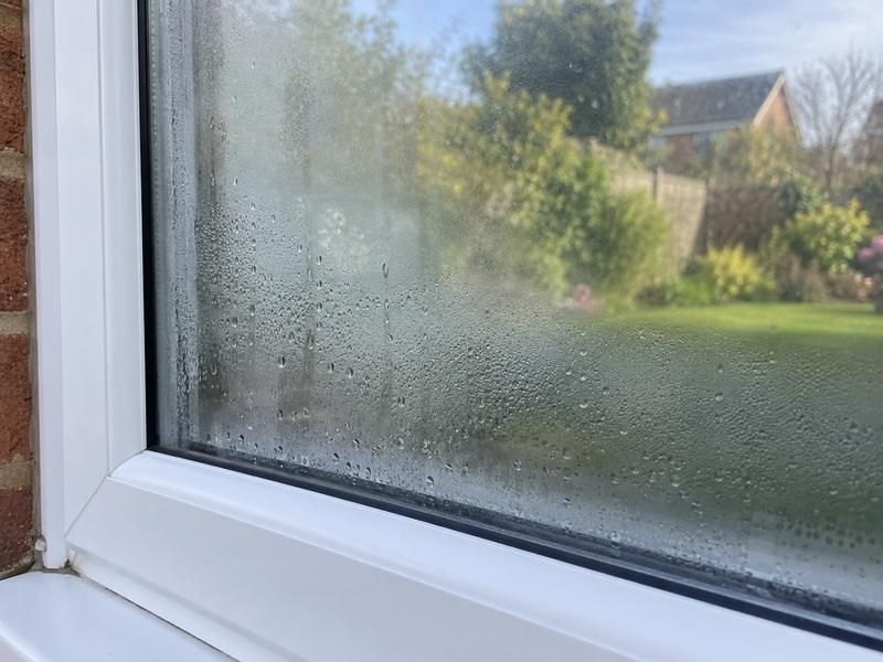 Double glazed window with mist and water droplets trapped between the panes