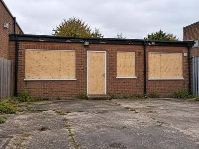 Rear of an empty commercial unit with its door and windows boarded