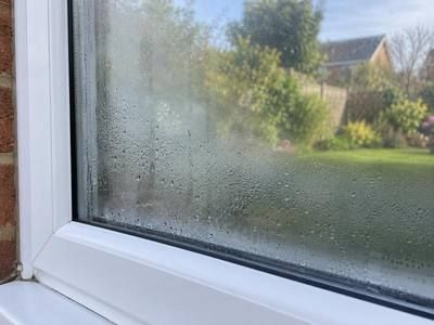 Double glazed window with mist and water droplets trapped between the panes