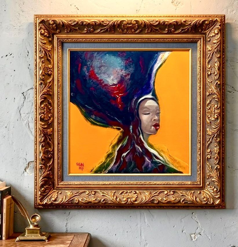 Ingelijst abstract portret met een sierlijke gouden lijst aan de muur, met levendige blauwe, rode en gele tinten.