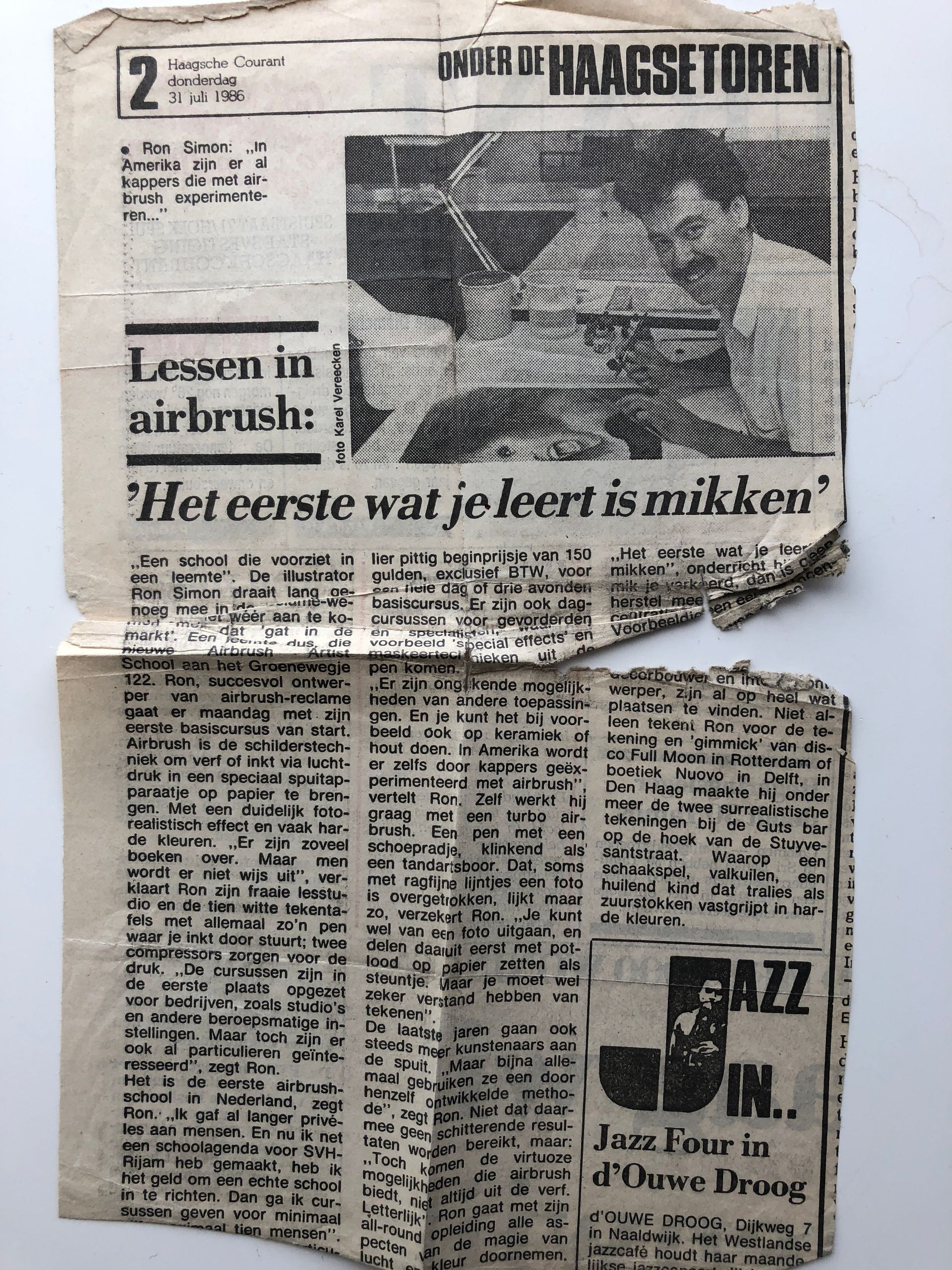 Korrelige zwart-wit krantenknipsel met een grote kop en artikelkolommen, gevouwen en versleten.