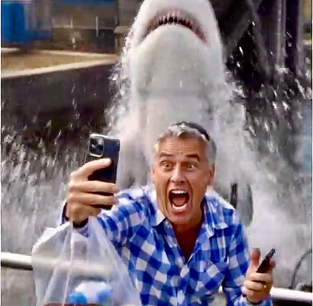 Een man maakt een selfie voor een springende haai in een waterpark en schreeuwt verbaasd.