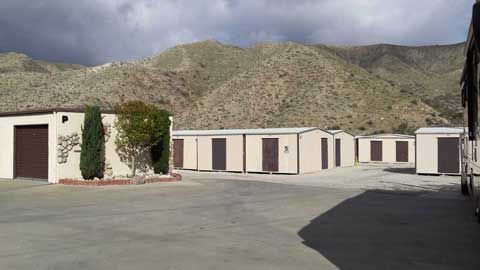 A row of buildings in a parking lot with mountains in the background.