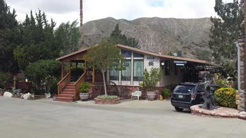 A house with a car parked in front of it and mountains in the background.