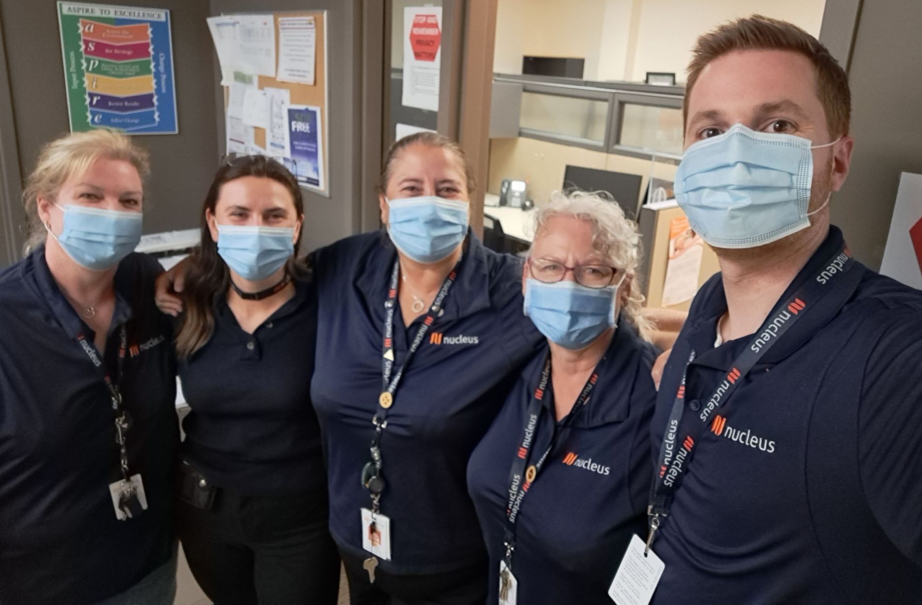 A group of people wearing face masks are posing for a picture.