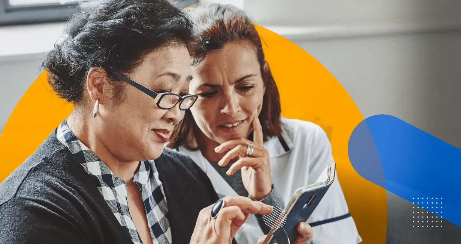 Two women are looking at a cell phone together.