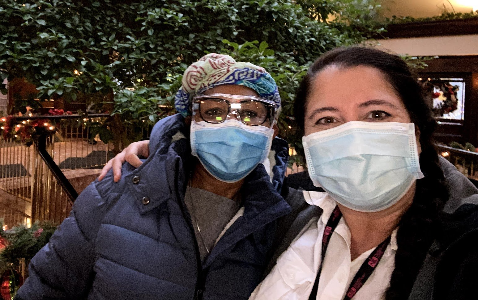 Two women wearing face masks and glasses are posing for a picture.