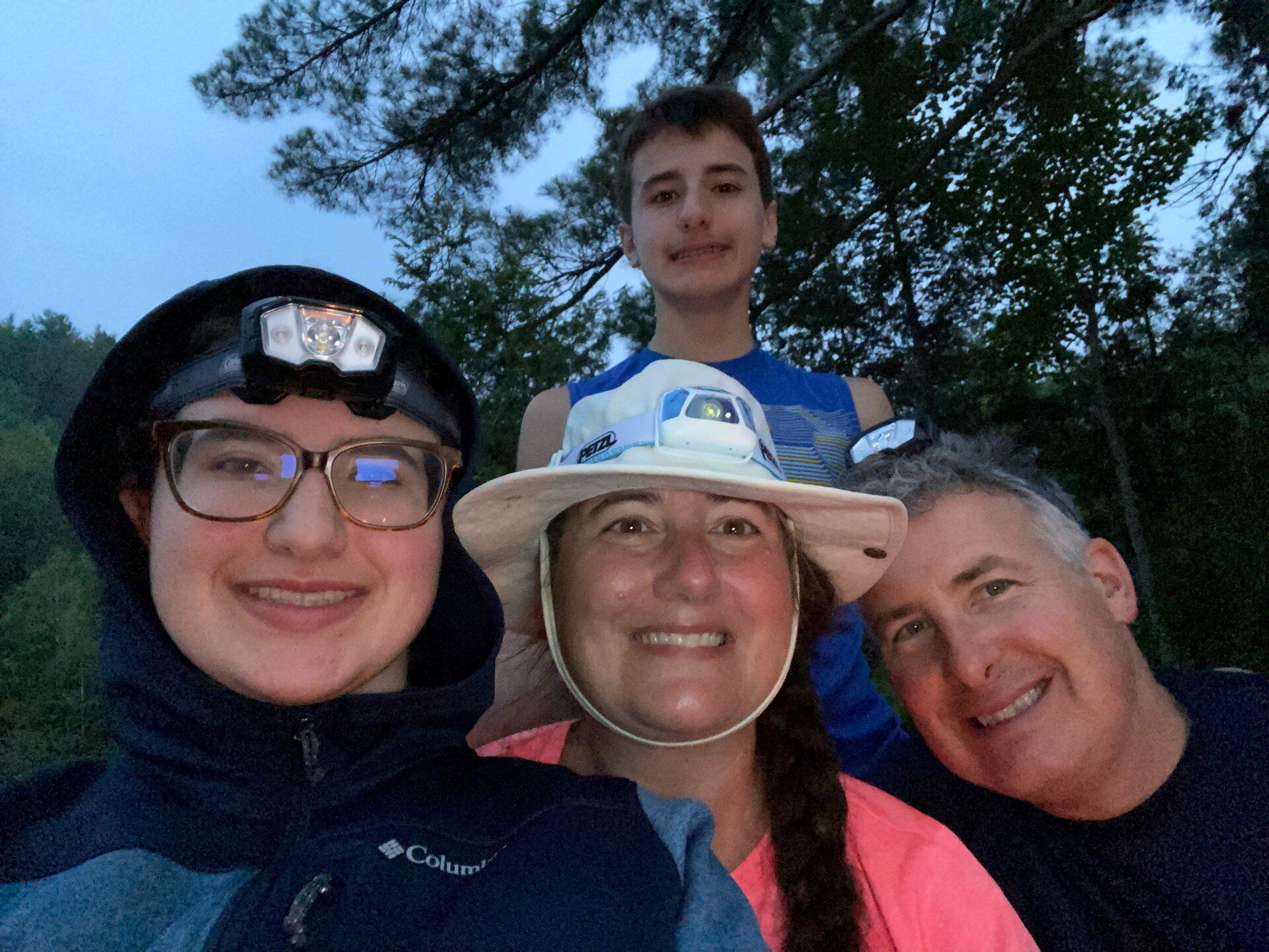 A family is posing for a picture together in the woods.