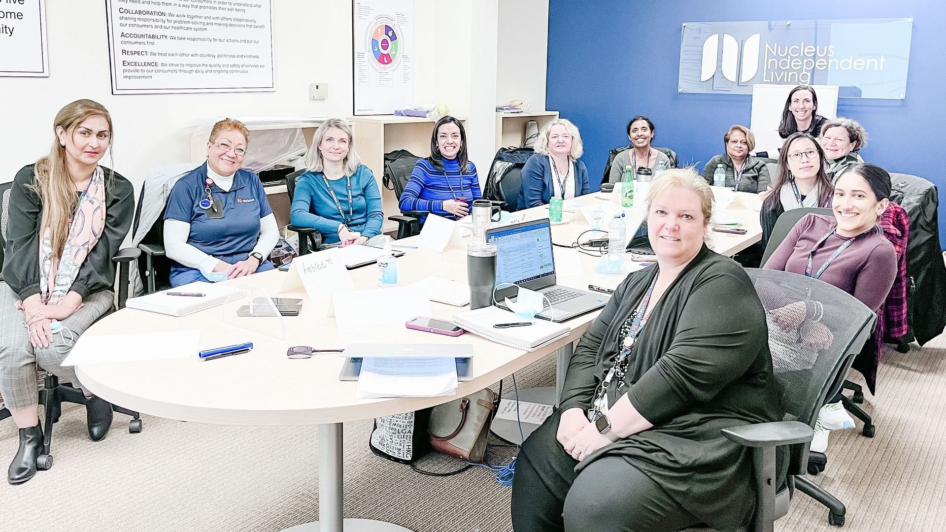 A group of women are sitting around a table in an office.