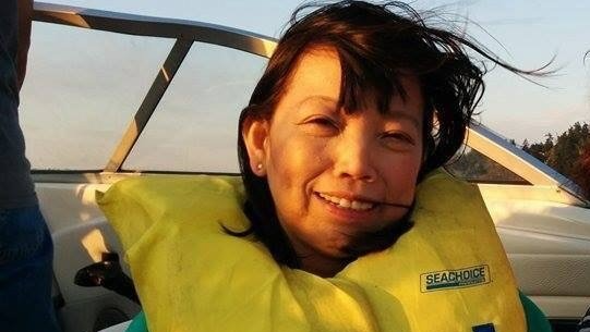 A woman wearing a yellow life jacket is smiling on a boat