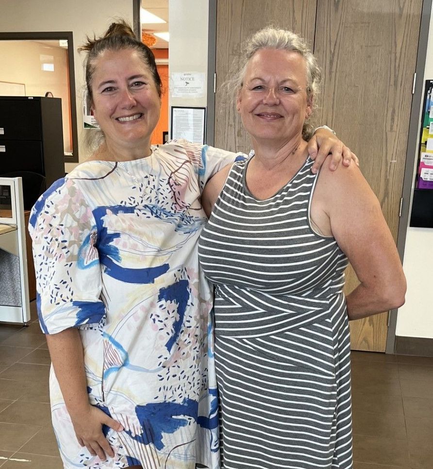 Two women are posing for a picture and one is wearing a striped tank top