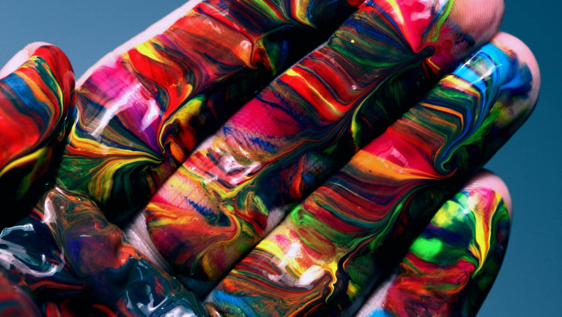 A close up of a person 's hand covered in colorful paint.