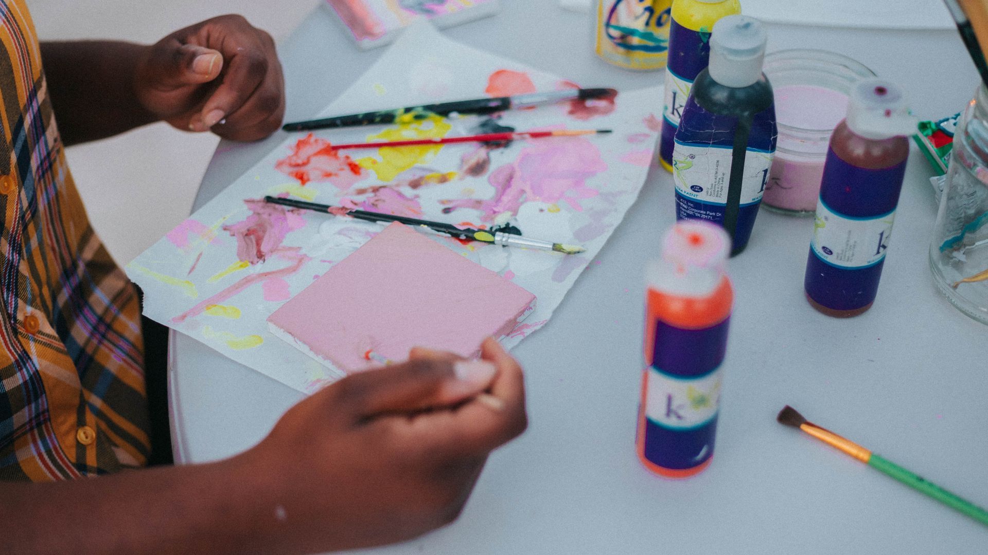 A person is sitting at a table painting with a brush.