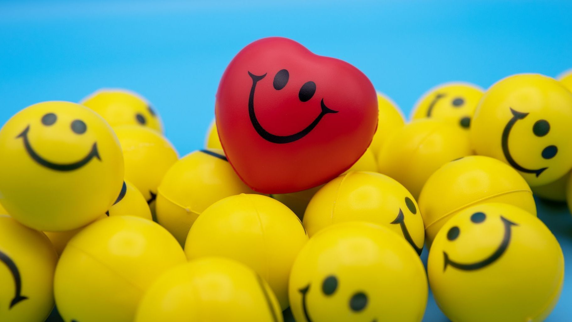 A red heart with a smiley face on it is surrounded by yellow smiley faces.