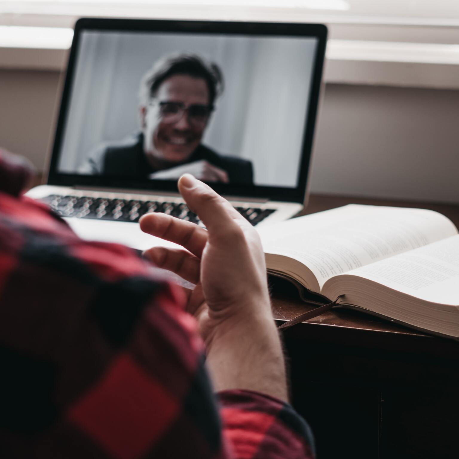 A person is sitting in front of a laptop with a picture of a man on the screen