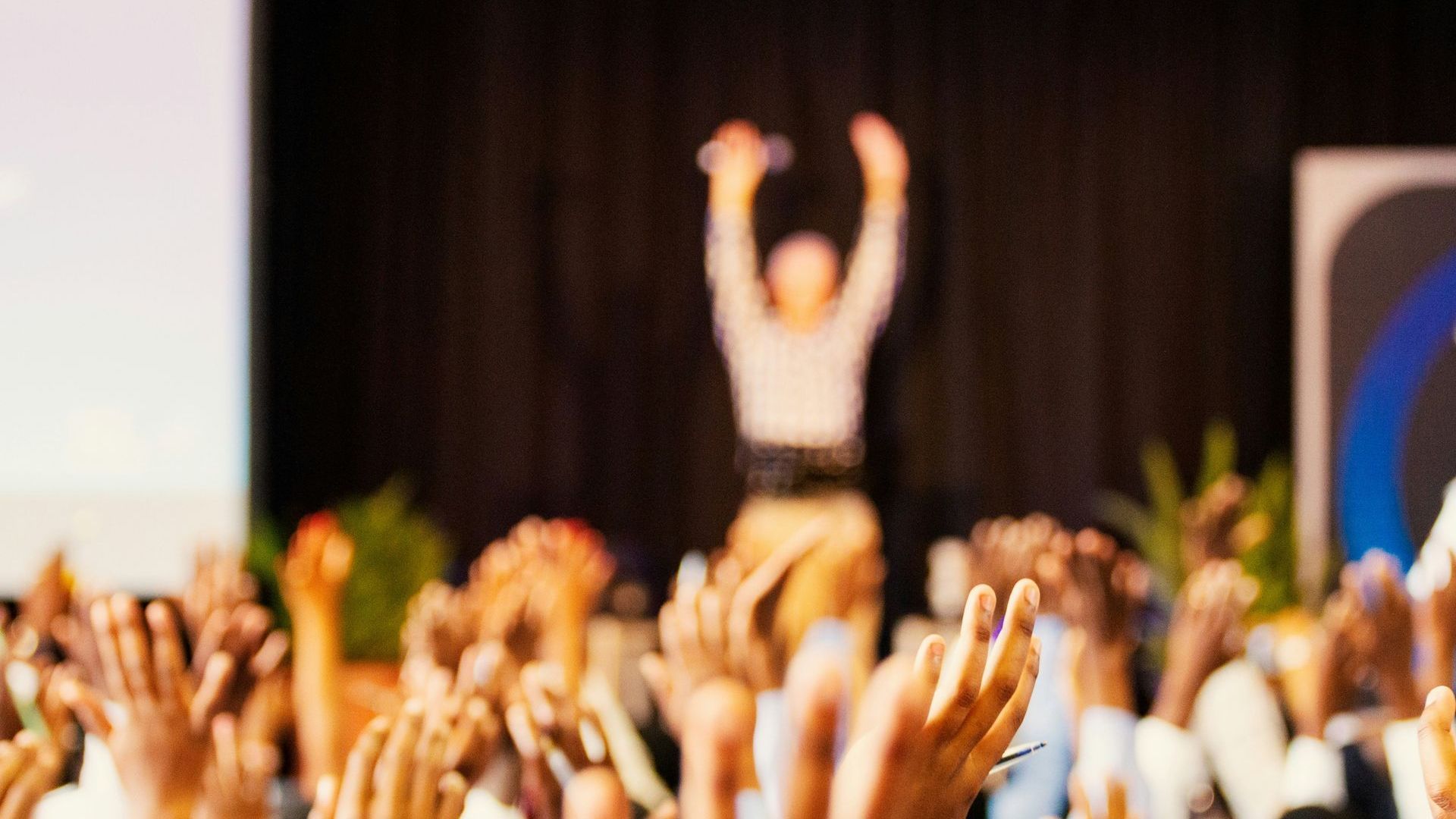 A crowd of people are raising their hands in the air at a concert.