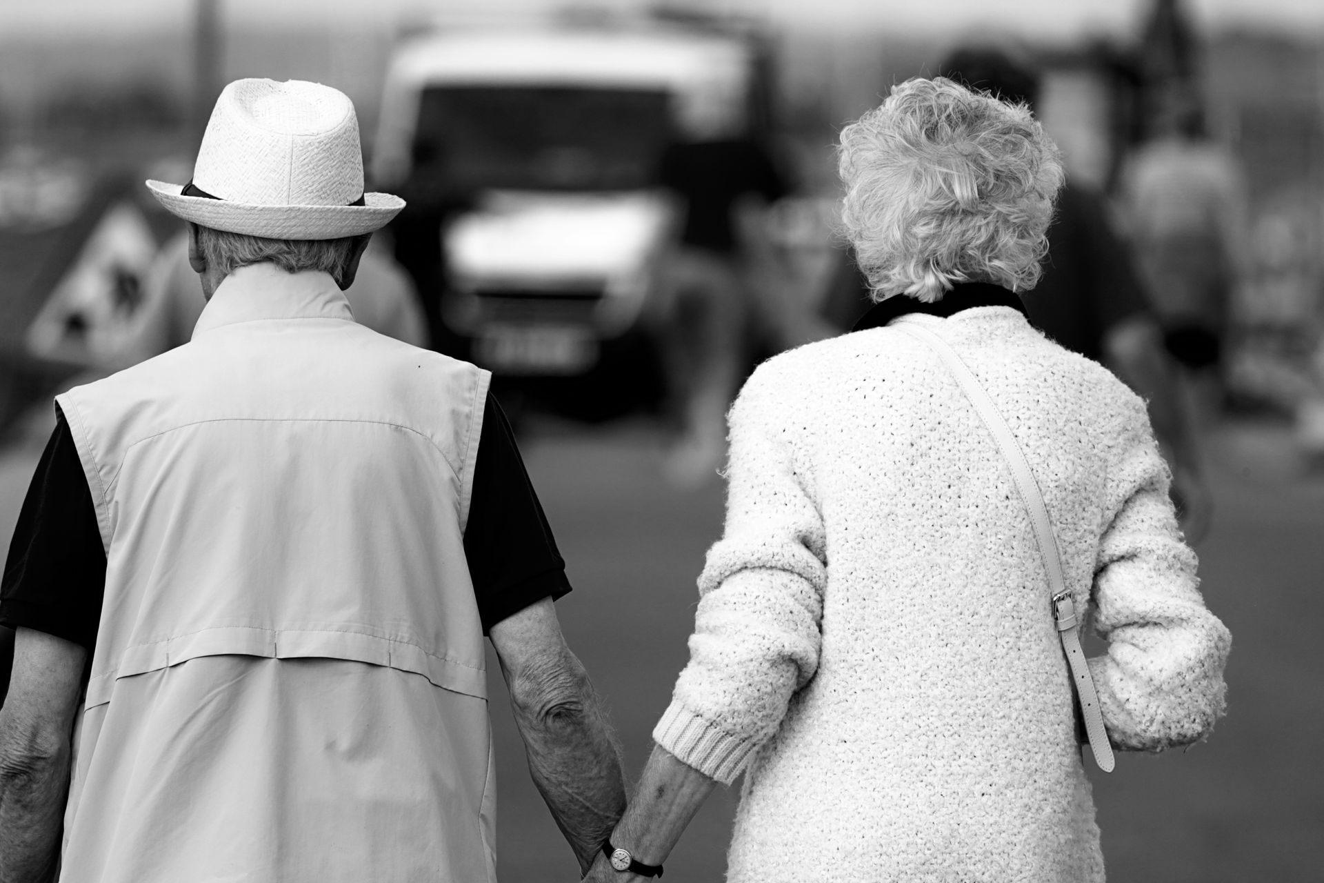 A man and a woman are holding hands while walking down a street.