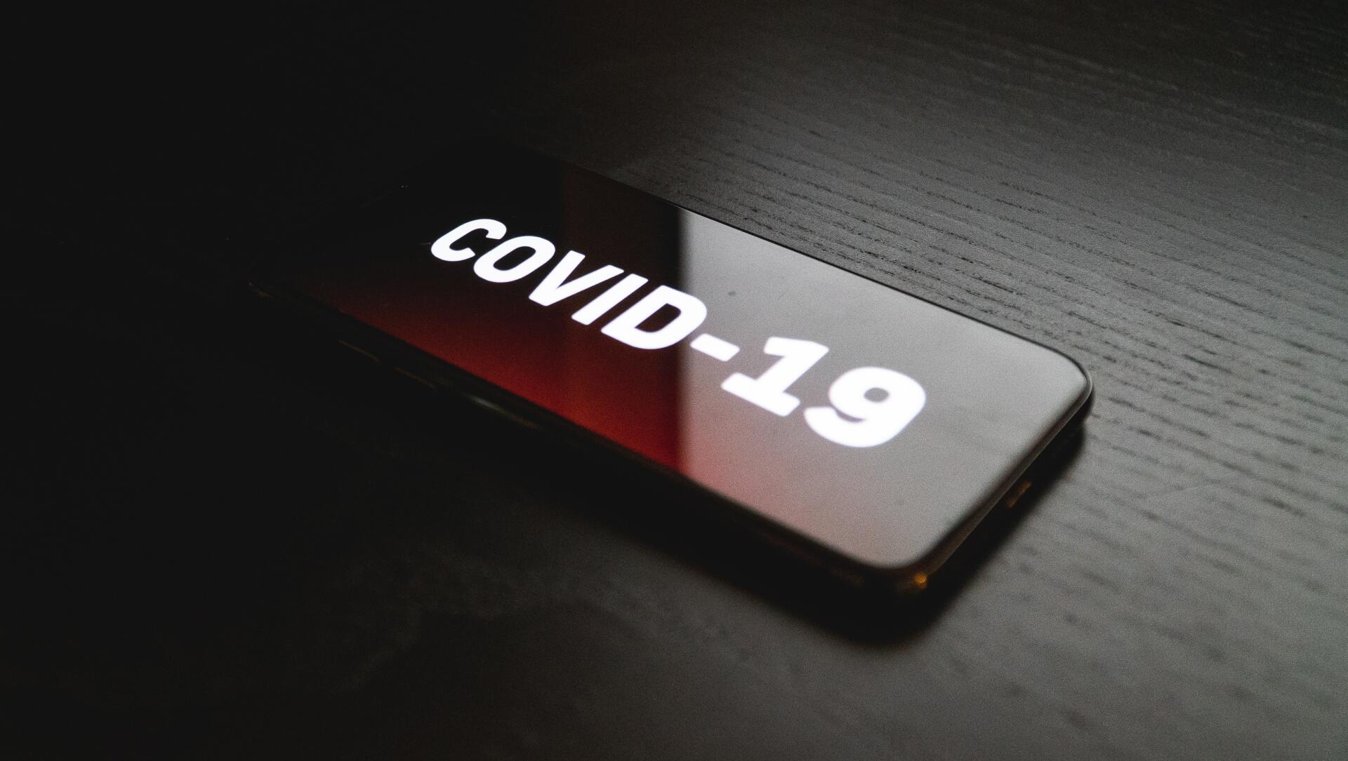 A cell phone with the word covid-19 on it