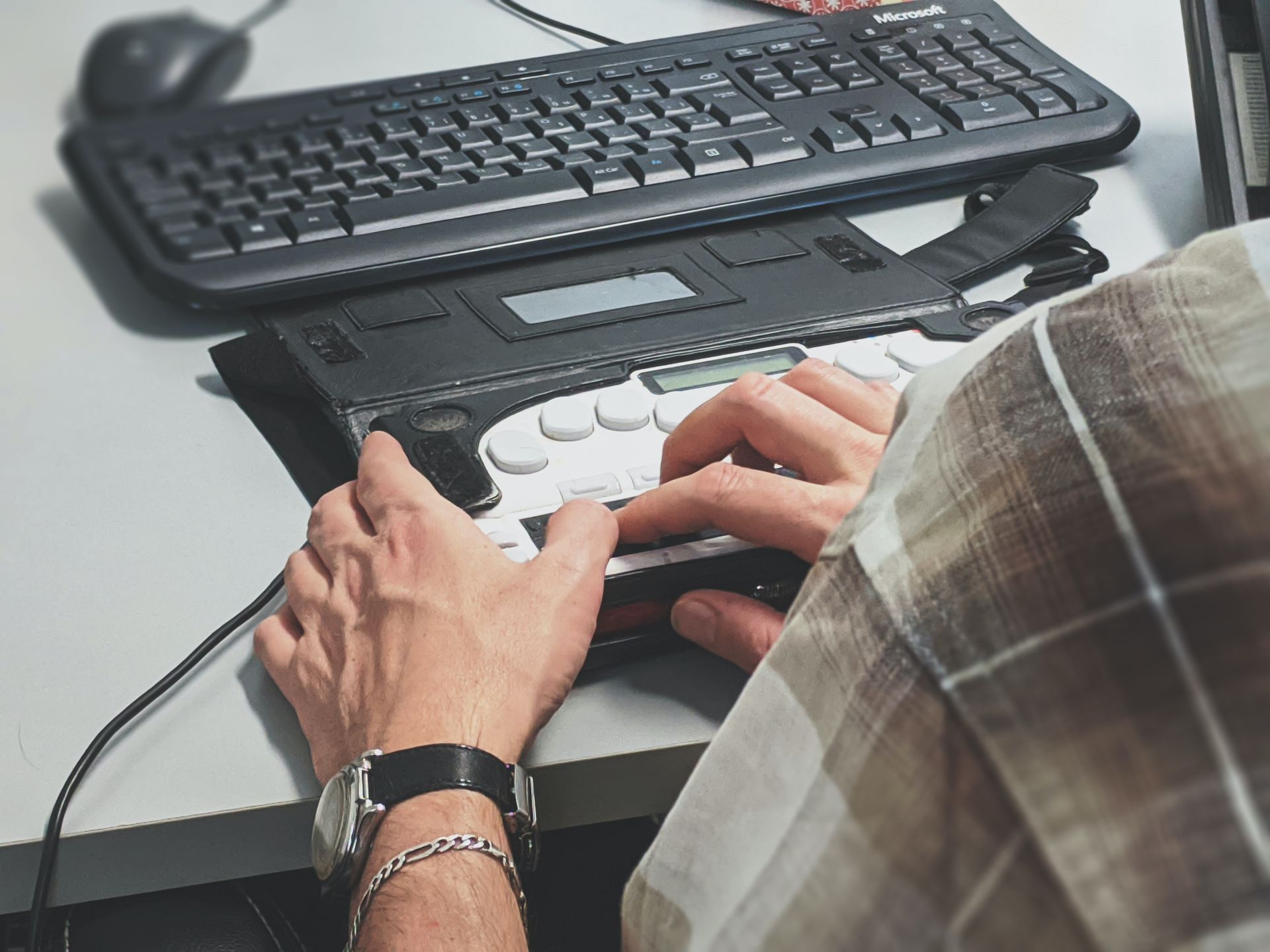 A person is typing on a braille keyboard