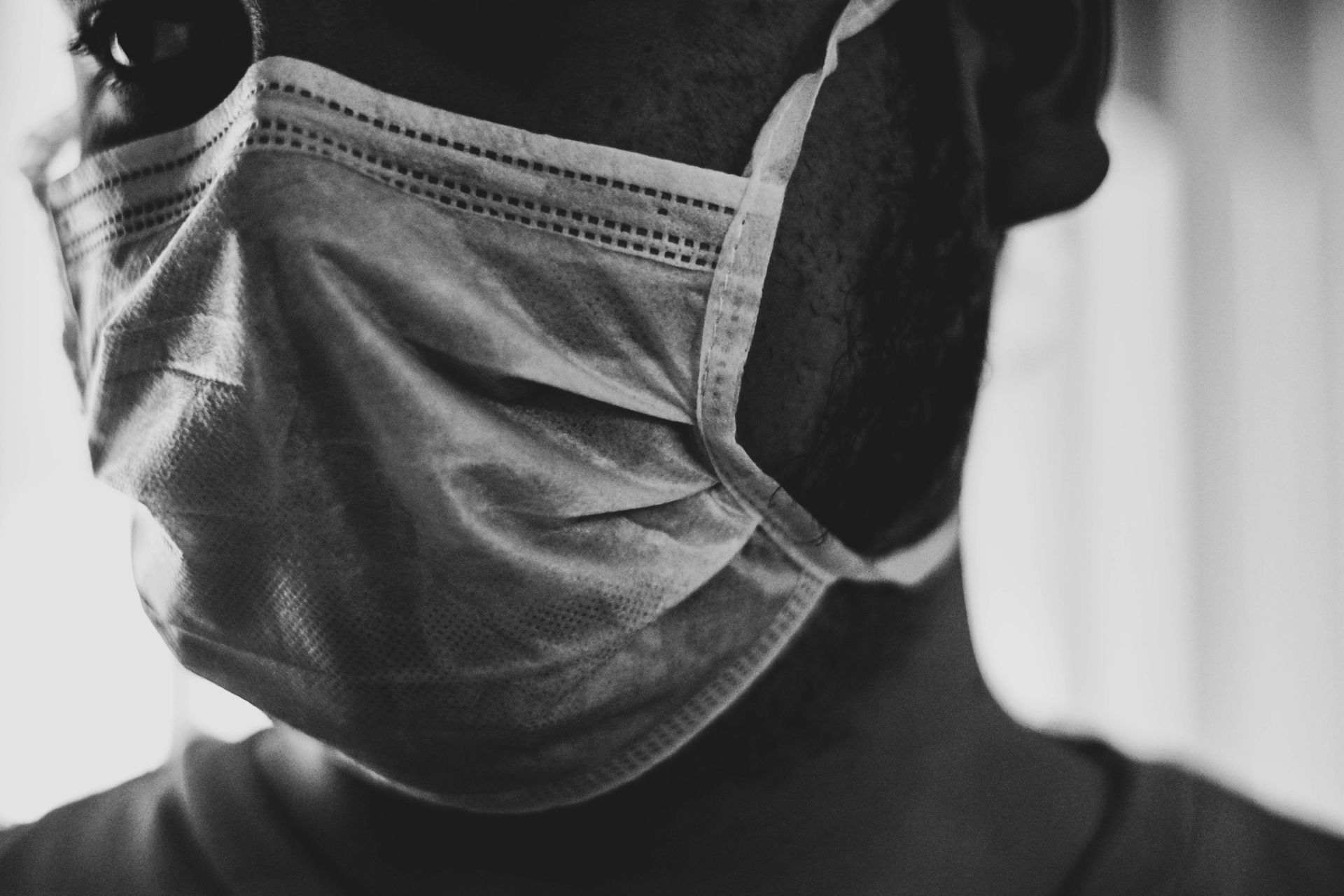 A black and white photo of a man wearing a medical mask.