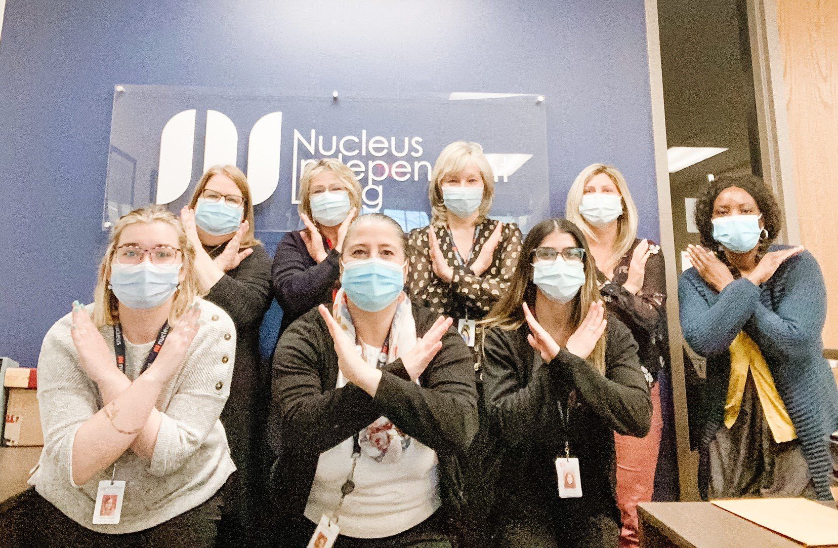 A group of women wearing face masks are posing for a picture.