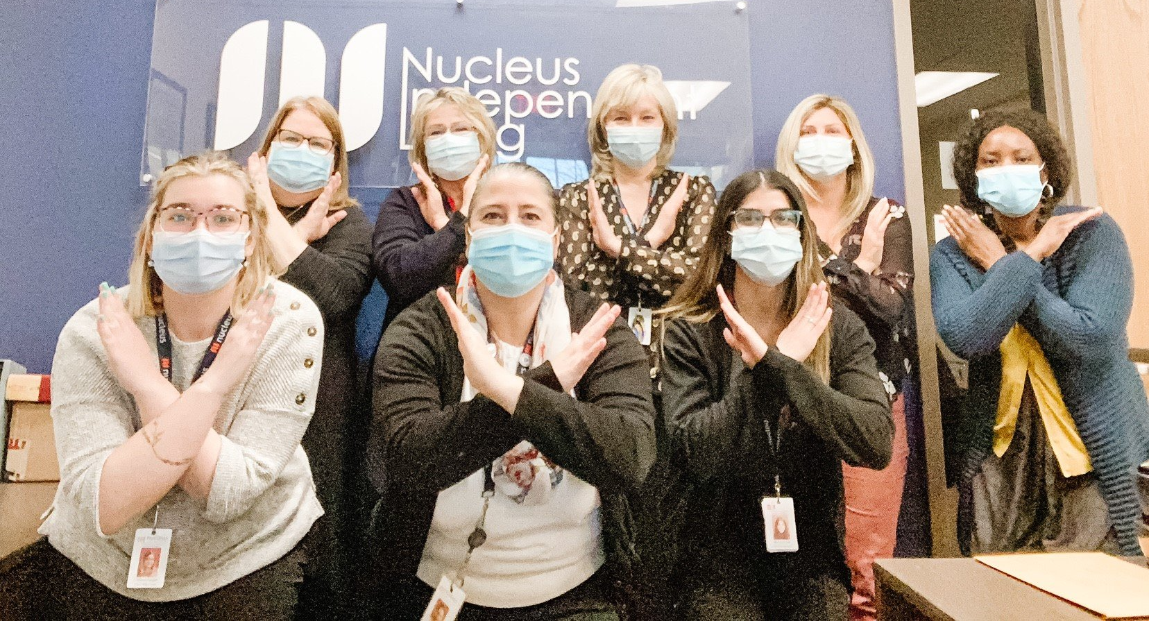 A group of women wearing face masks are posing for a picture.