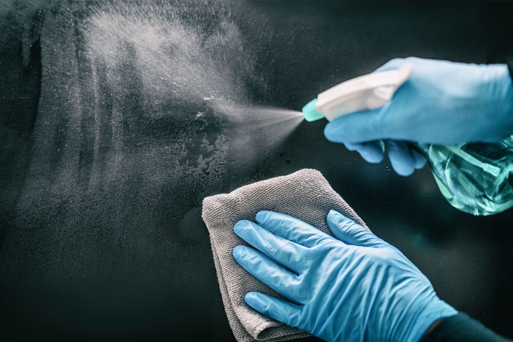 Person In Blue Gloves Spraying Cleaner On A Surface, Wiping With A Gray Cloth —Your Expert Cleaners in Toowoomba