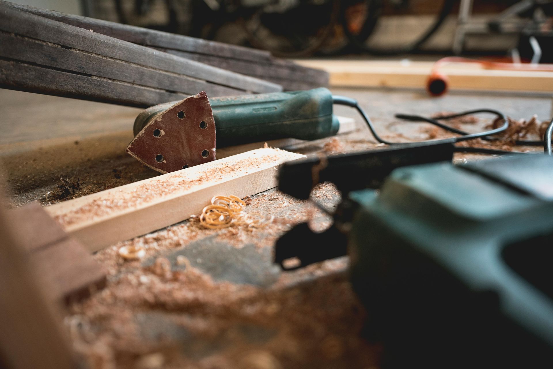 Green power tools and wood shavings on a concrete floor in a workshop. — Serena's Local Cleaning Company In Toowoomba, QLD