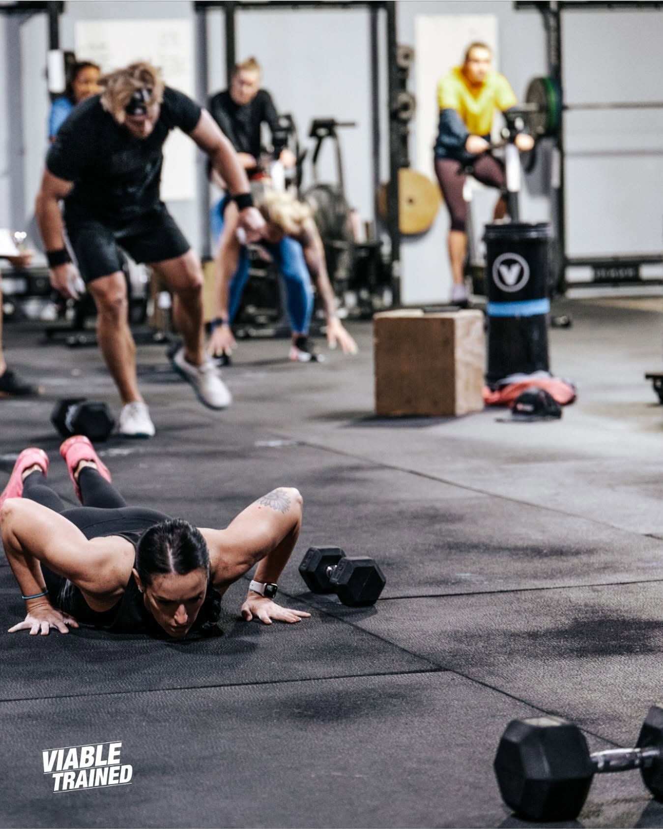 Woman doing a lunge with dumbbells on a mat outdoors during a workout class at the best CrossFit gym in Sioux Falls, SD.