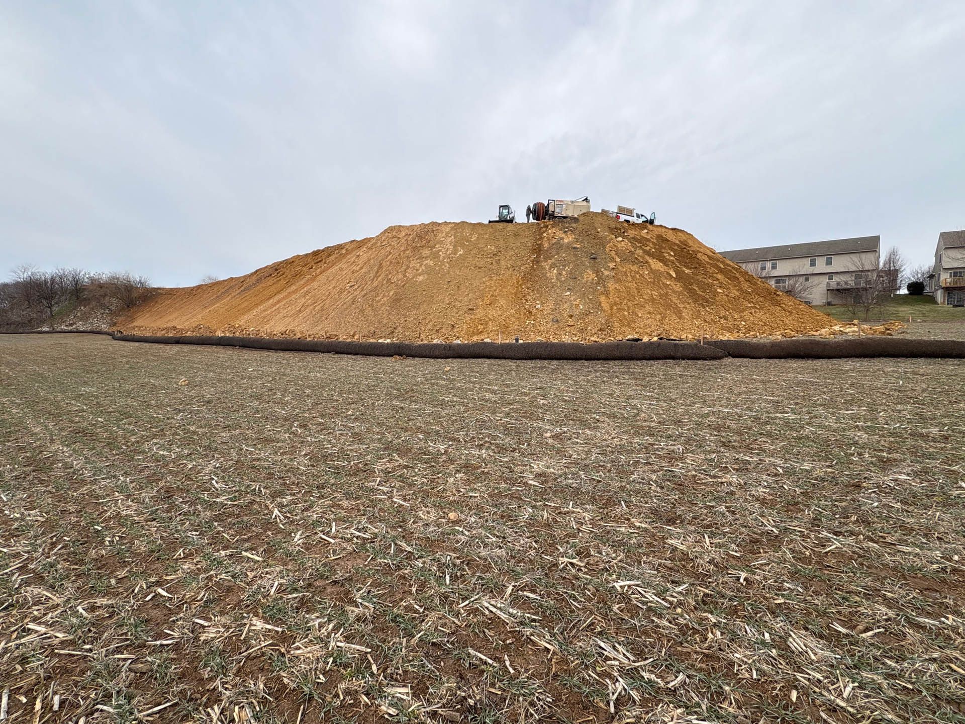 Large pile of wood chips on a field in Lancaster PA; heavy machinery on top.