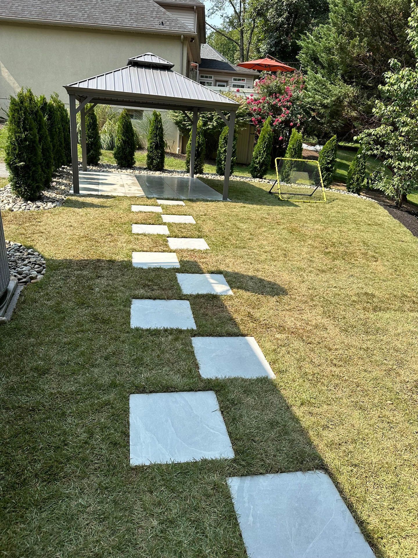 Stone pathway through grass leads to gazebo.