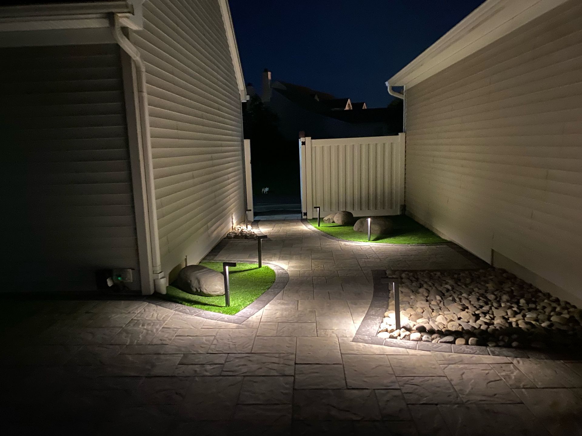 A walkway between two houses is lit up at night.