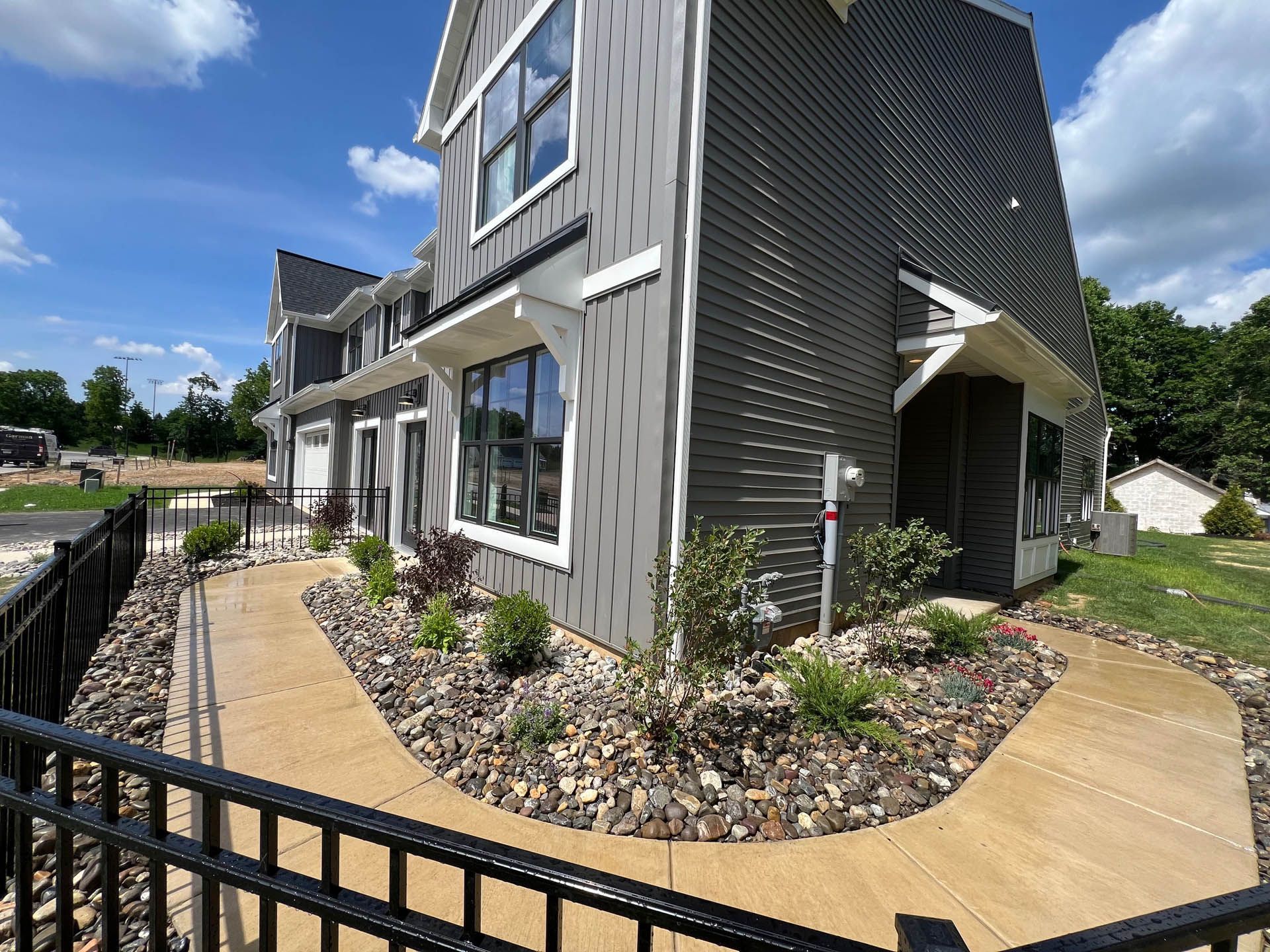 Gray townhouses with white trim, pathway, and black metal fence.