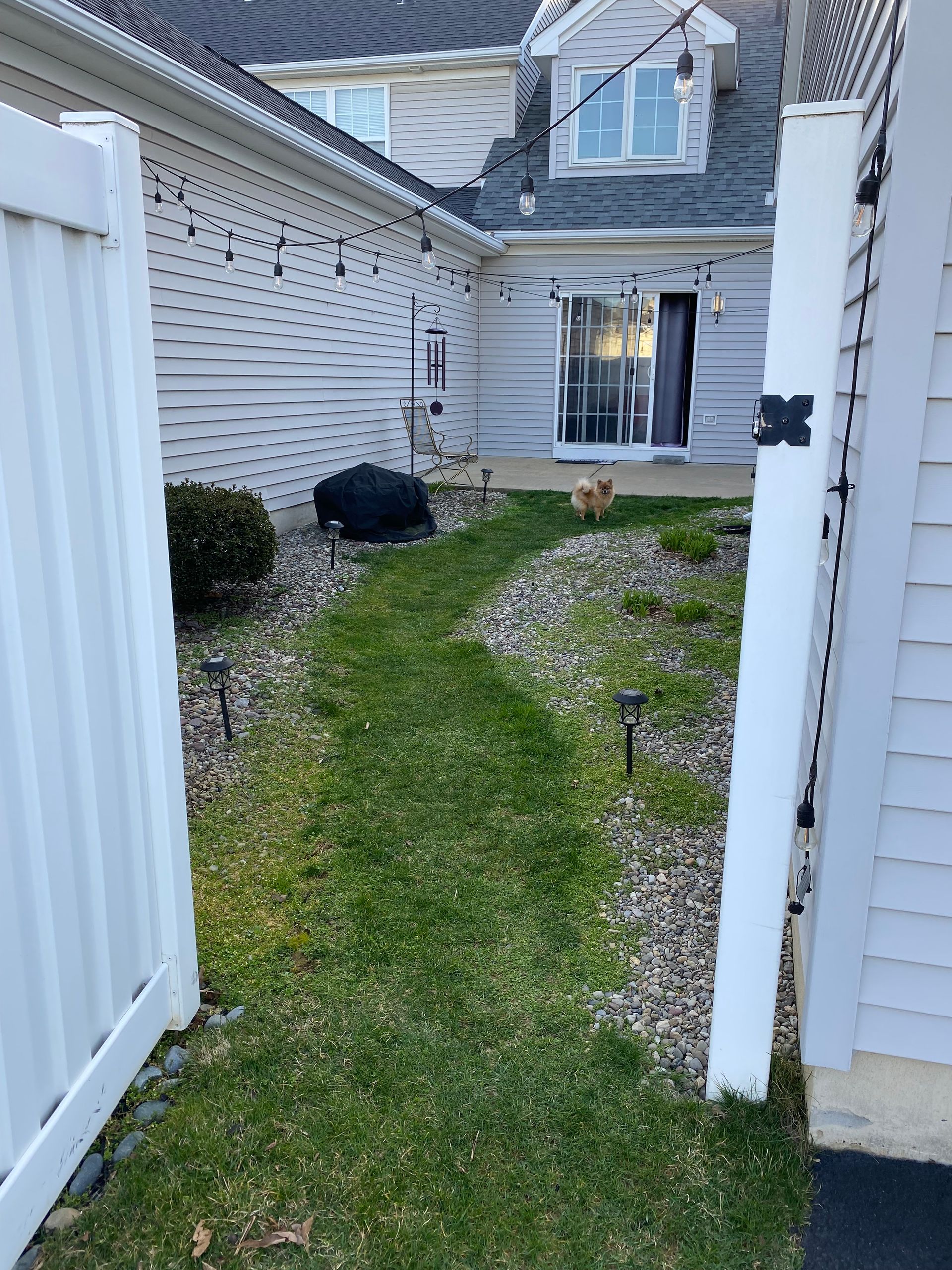 A white fence leading to a house with a sliding glass door.