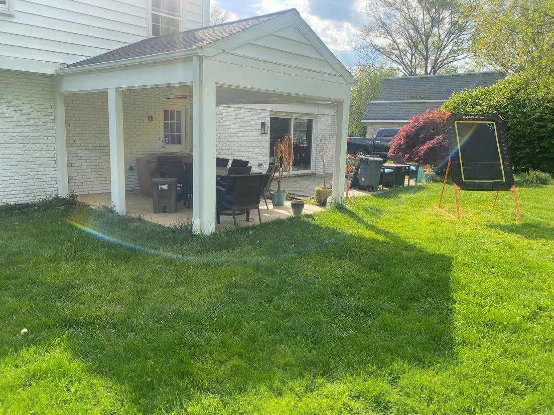 There is a covered patio in the backyard of a house.