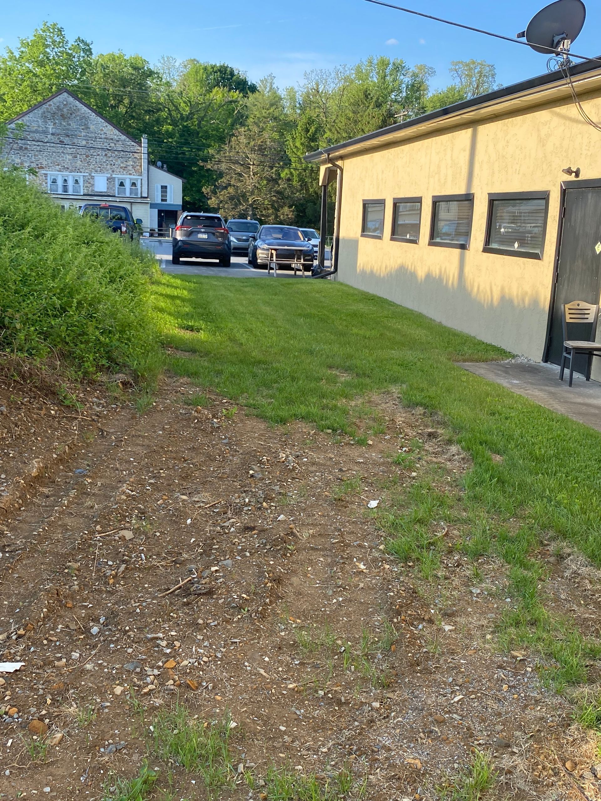 A row of cars are parked in front of a yellow building.