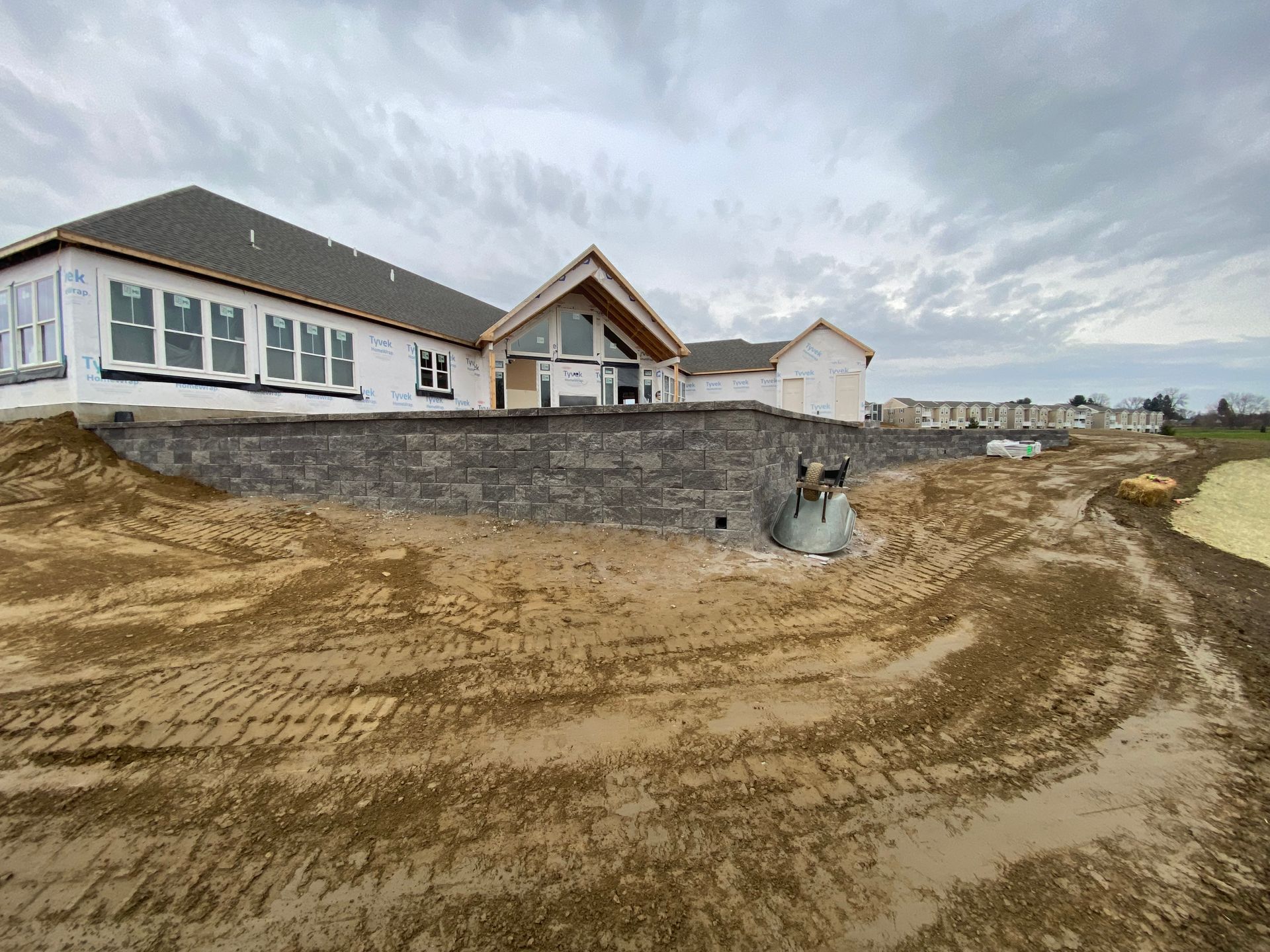 A large house is being built on top of a dirt hill.