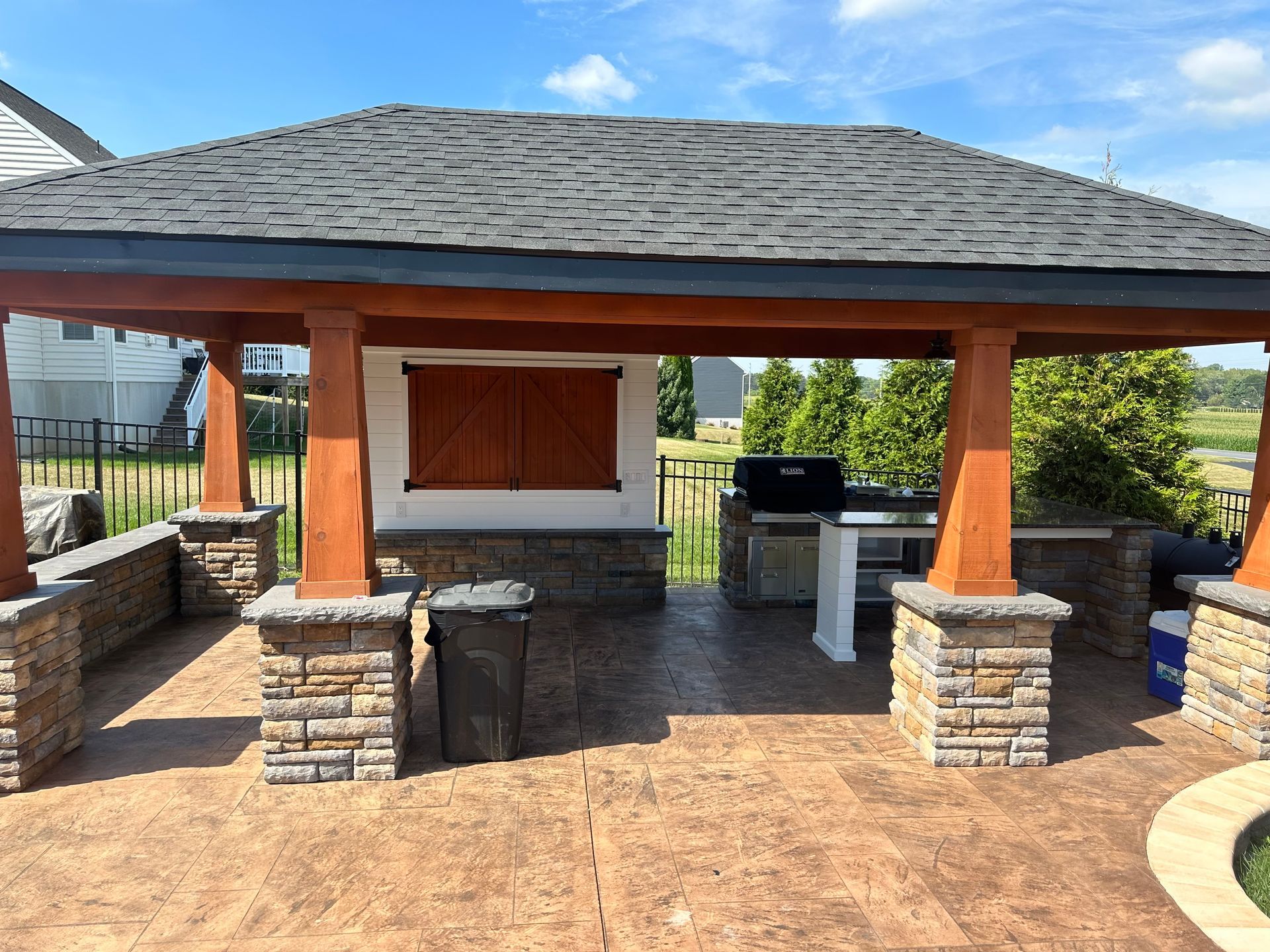 A gazebo with a grill underneath it and a wooden roof installed by complete property solutions of Lancaster PA