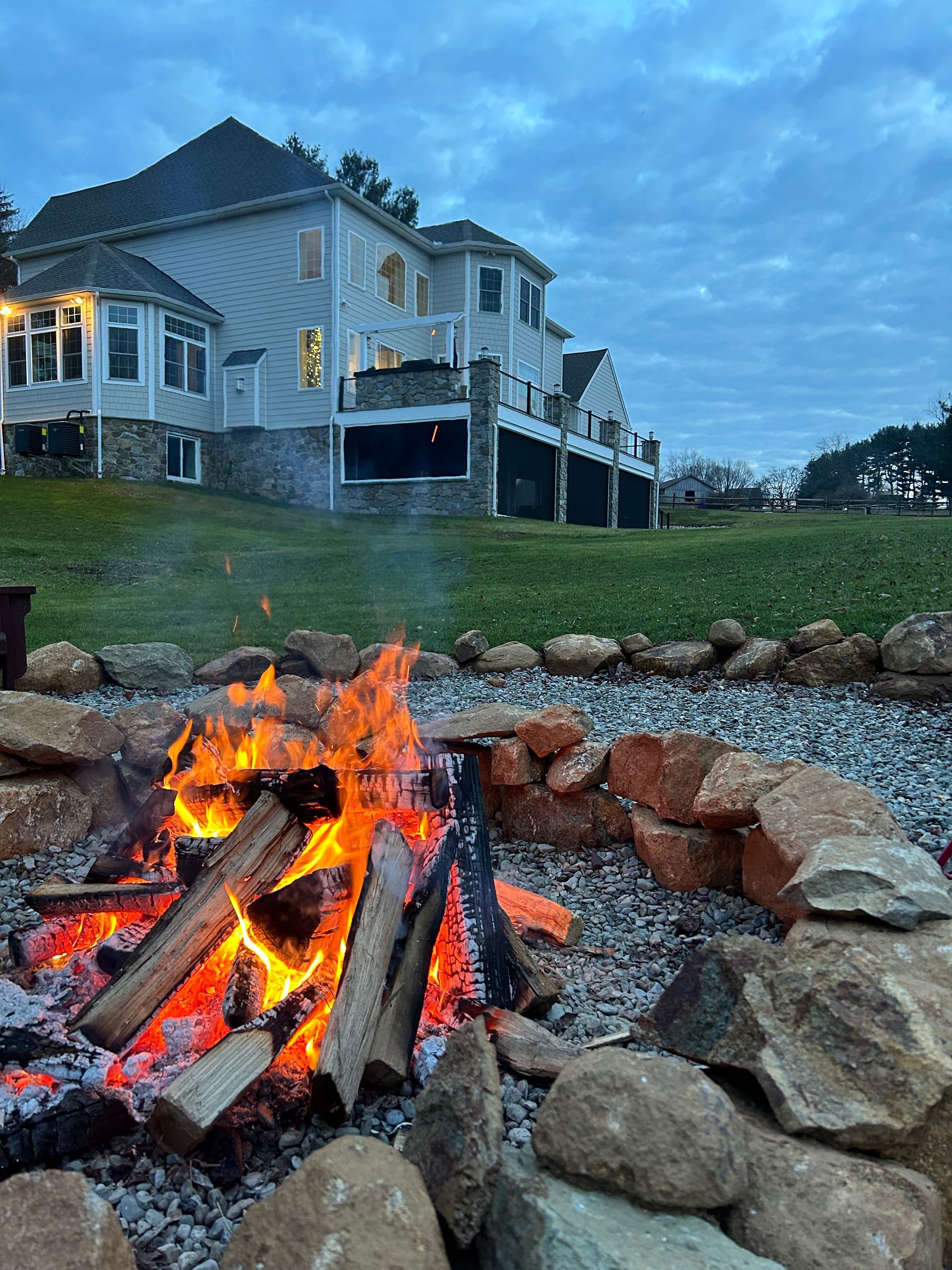 A fire pit with a large house in the background